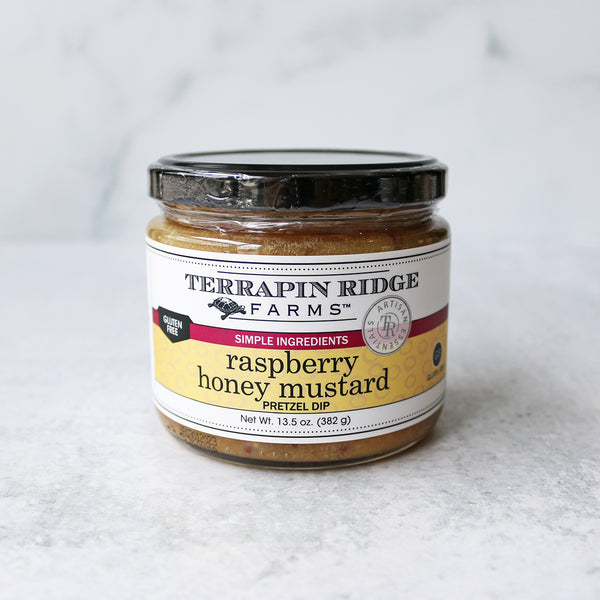 A jar of Terrapin Ridge Farms Raspberry Honey Mustard Pretzel Dip on a marble surface.