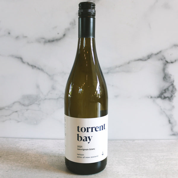 A bottle of Torrent Bay Sauvignon Blanc wine positioned in front of a marble background.