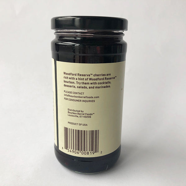 A jar of Woodford Reserve Bourbon Cherries with a label that includes the brand name and the product name. The jar is sealed and placed against a white background.
