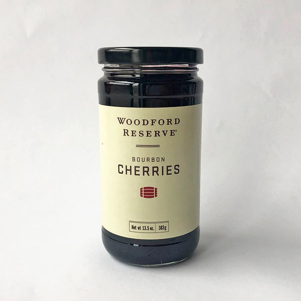 A jar of Woodford Reserve Bourbon Cherries with a label that includes the brand name and the product name. The jar is sealed and placed against a white background.